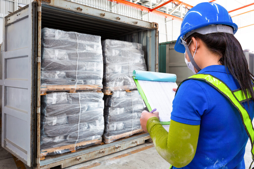 Woman in a hard hat checking a list of items in a container